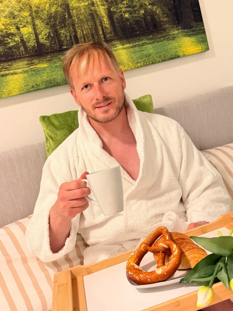 Gast im Bademantel beim Frühstück mit Kaffee und Brezn